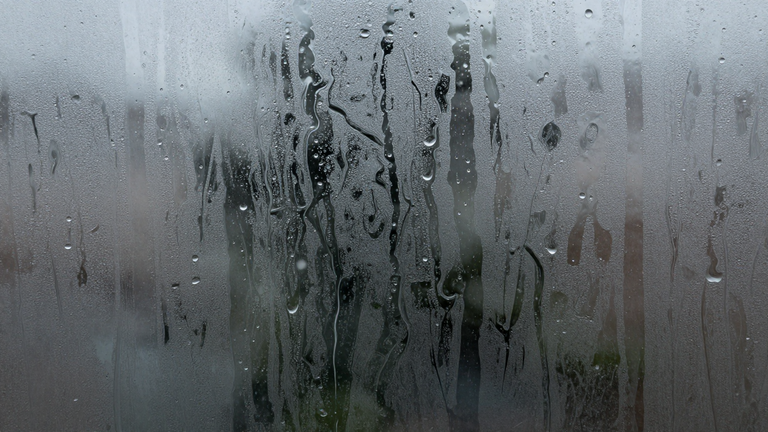 Ein Fenster von außen fotografiert, Wasser tropft und spritzt an der Scheibe herunter, subtiler Bezug zum Squirting, abstrakt und künstlerisch